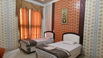 Two single beds with headboards and pillows, patterned wallpaper, and a window with curtains.