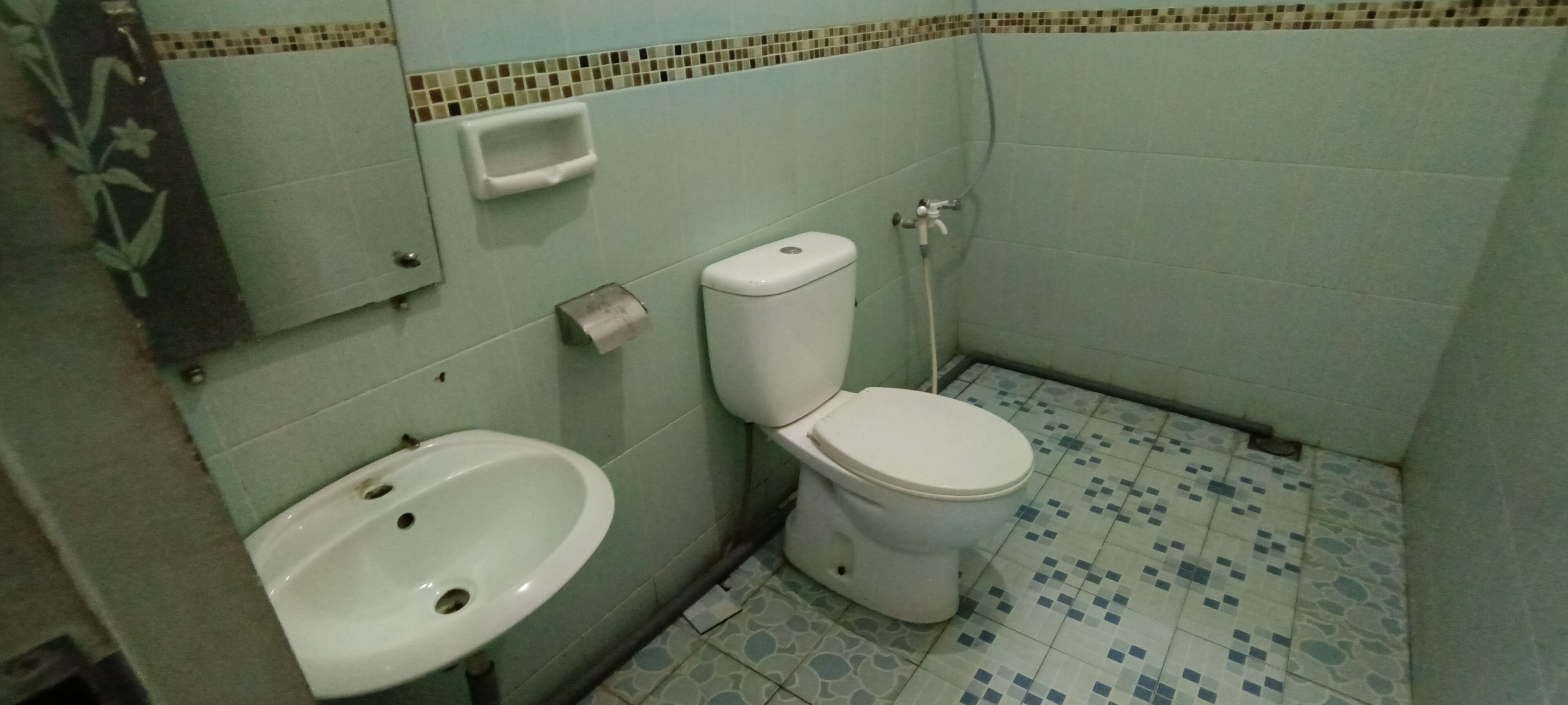 Une salle de bain avec des toilettes, un lavabo et un sol carrelé.