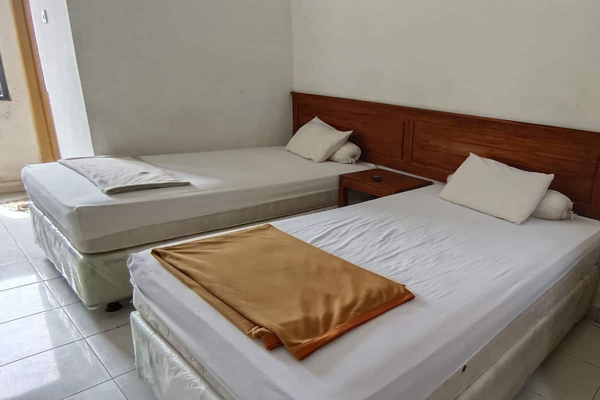 A hotel room with two beds, a wooden headboard, and a bedside table with a remote control.