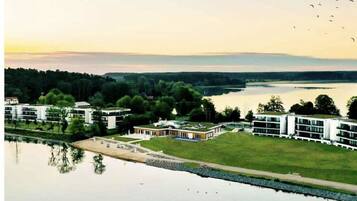 Ein Hotel am Seeufer, mit moderner Architektur, einer Rasenfläche und einem ruhigen See.