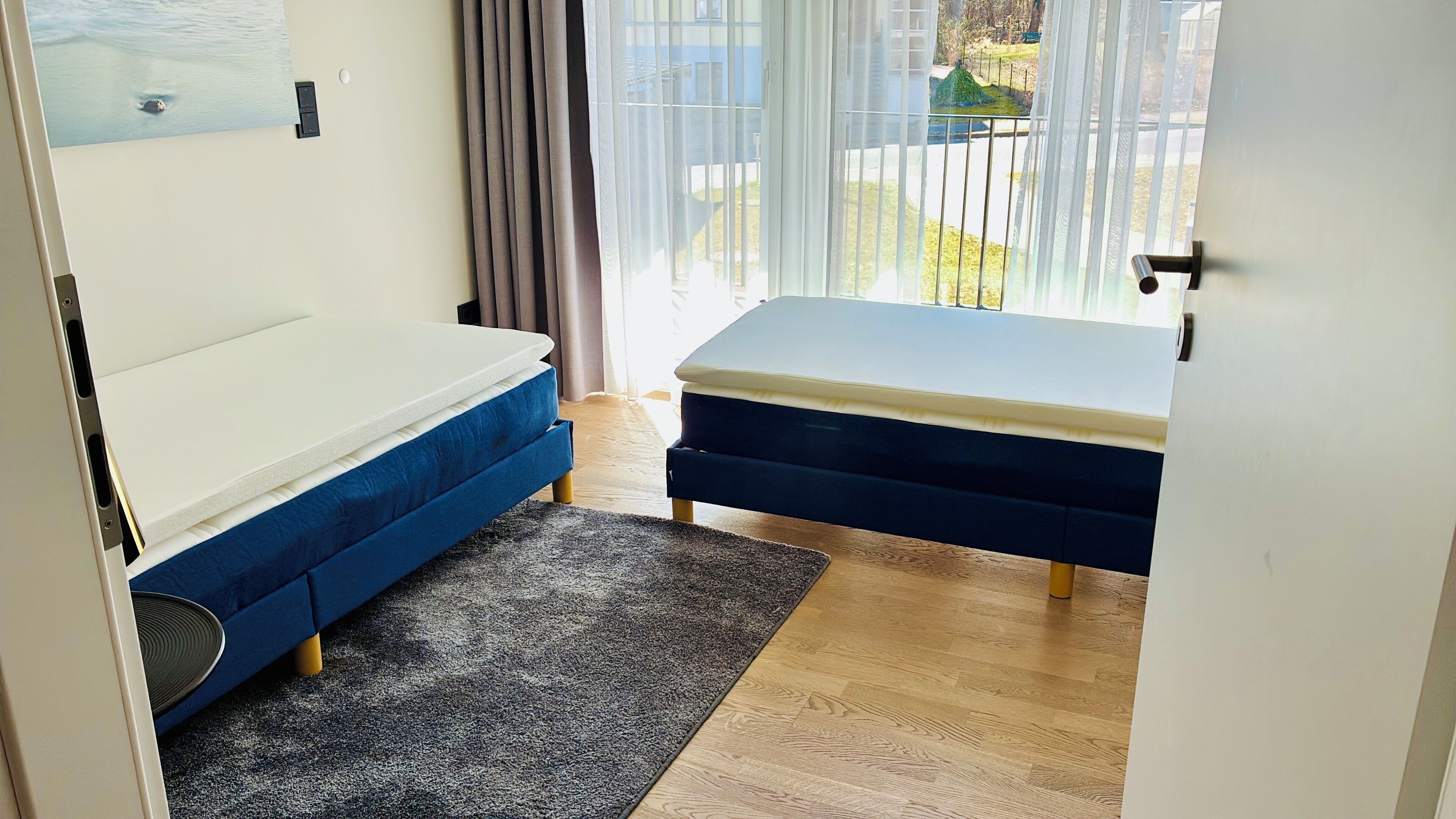 Une chambre à coucher avec un lit, une petite table et une vue sur l’extérieur par une fenêtre.