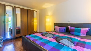 A bedroom with a bed, a wardrobe, and a bedside lamp. - Hafenriff - Appartement 1 (Sassnitz)