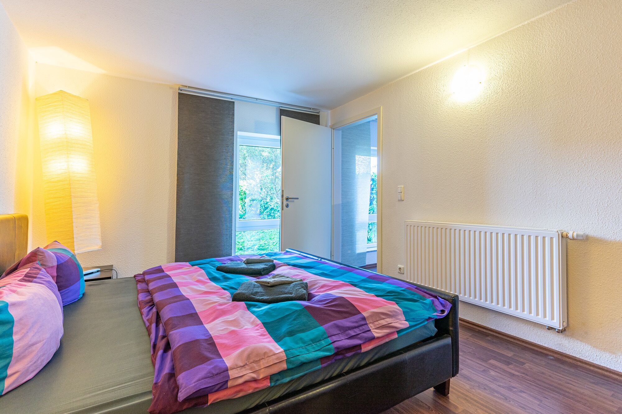 A bedroom with a bed, a window, and a radiator.