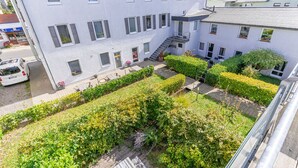 A multi-story building with a courtyard featuring neatly trimmed hedges and a paved walkway. - Hafenriff - Appartement 4 (Sassnitz)