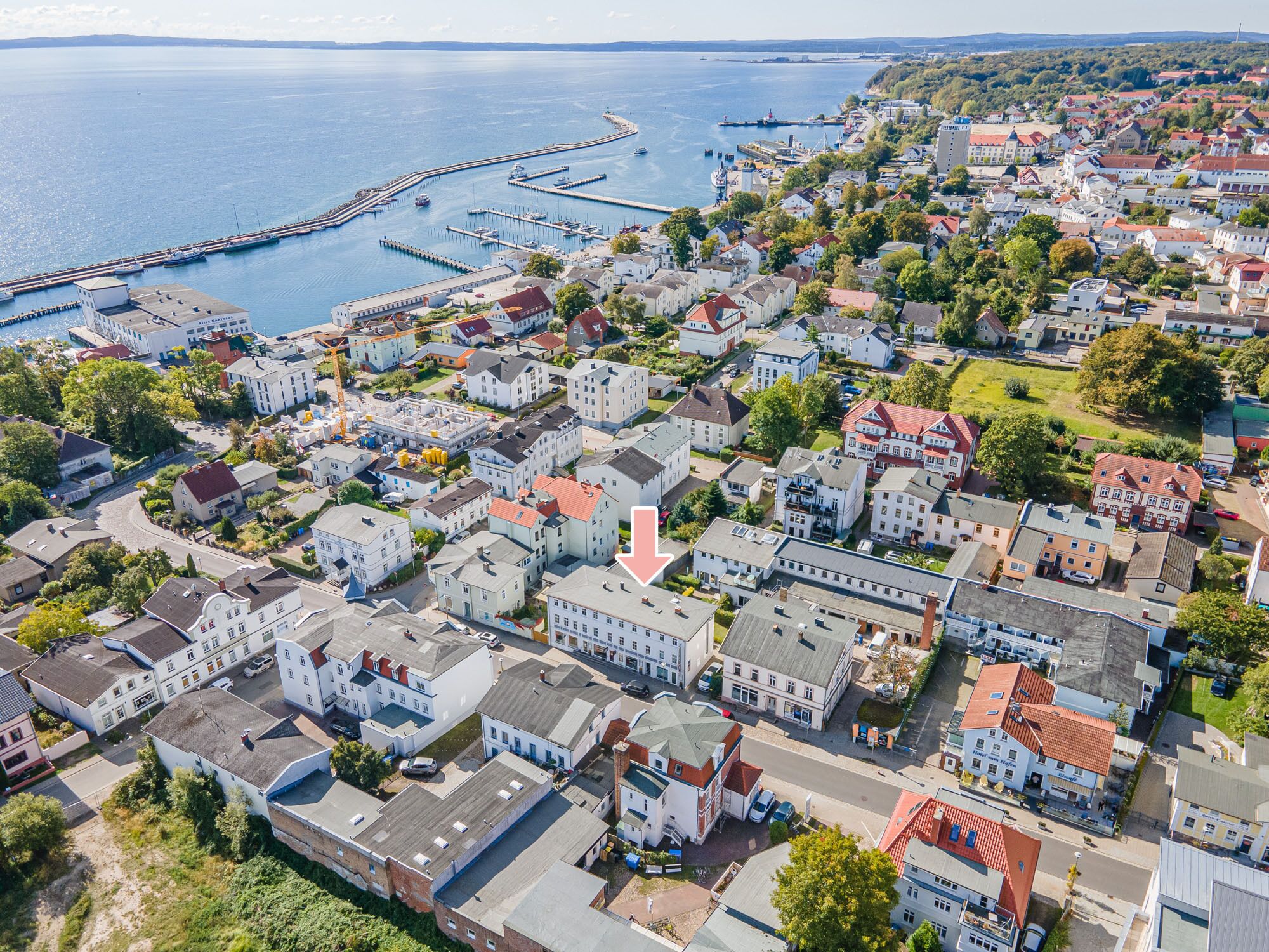An aerial view of a coastal town with residential buildings, a marina, and a pier.