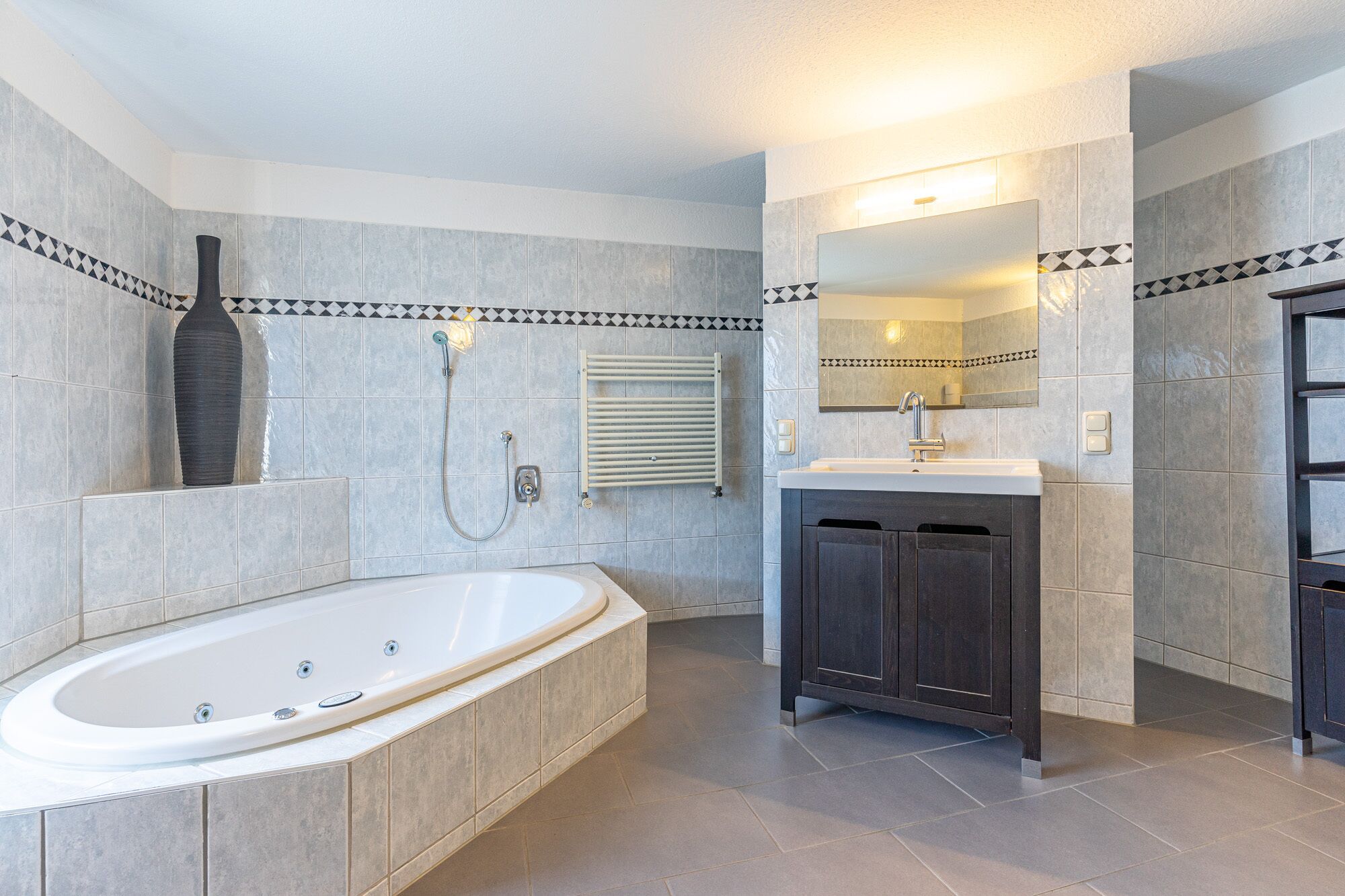 A modern bathroom with a freestanding bathtub, a vanity with a mirror, and a towel rack.