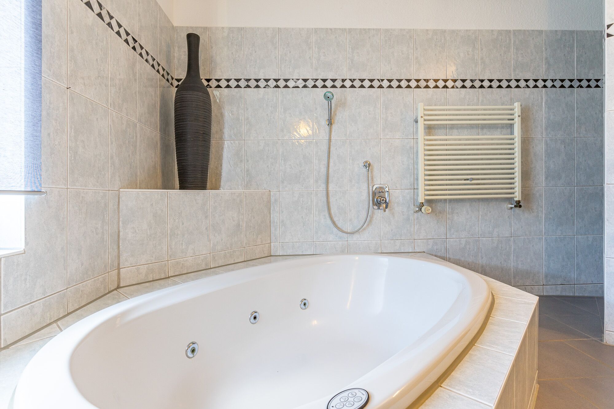 A modern bathroom with a large bathtub, a shower, and a towel rack.