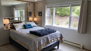 Une chambre à coucher moderne avec un grand lit, des lampes de chevet, un miroir et une vue sur l’extérieur.