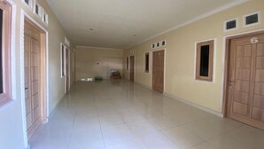 A long, narrow hallway with doors numbered 5 and 6, leading to individual rooms. - Capital O 93124 Lombok Northis Homestay (Tanjung)