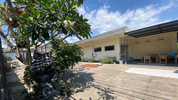 A courtyard with a building, potted plants, and a clear sky. - Capital O 93124 Lombok Northis Homestay (Tanjung)