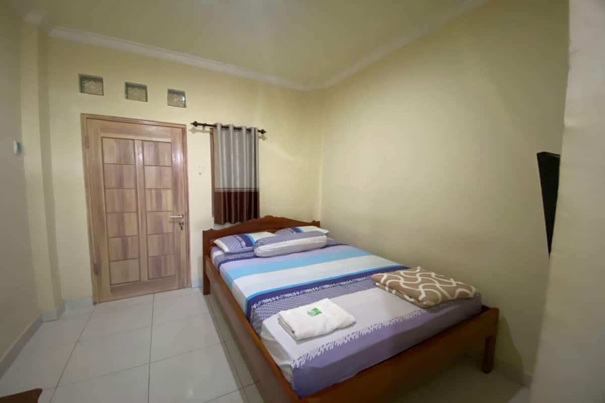 A bedroom with a bed, a wooden door, and a curtain.