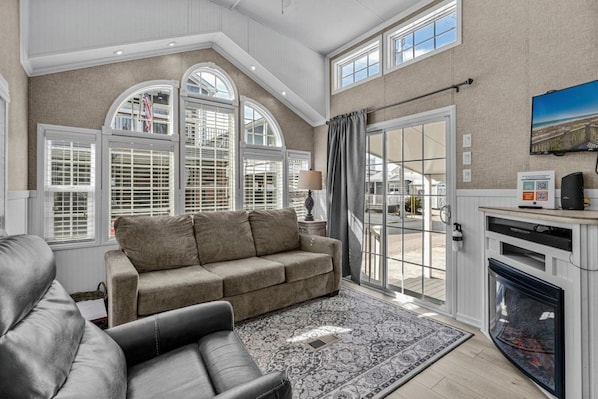A spacious living room with a large sofa, a smaller sofa, and a fireplace.