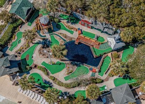 An aerial view of a golf course with multiple greens, a central water hazard, and surrounding trees. - Ocean Lakes Getaway, Beach Access and Outdoor TV (Myrtle Beach)