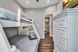 A bedroom with bunk beds, a dresser, and a hallway leading to another room. - Ocean Lakes Oasis, Golf Cart and Beach Access! (Myrtle Beach)