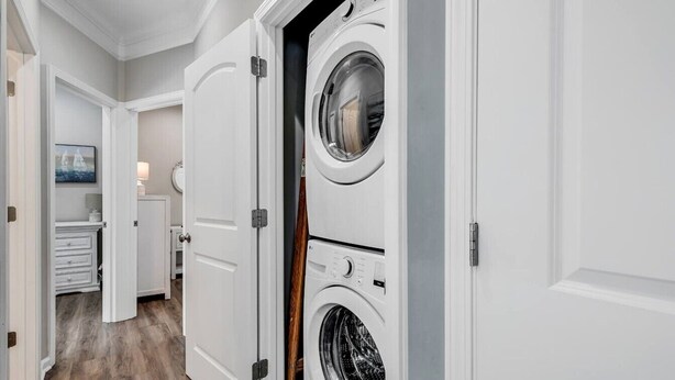 Une buanderie équipée de deux machines à laver à chargement frontal, avec un plancher en bois et un couloir menant à une salle de bain.