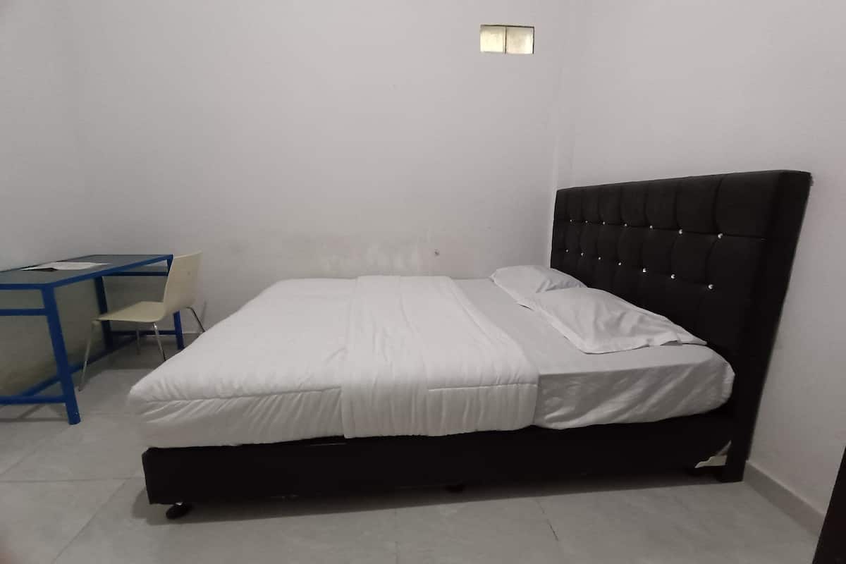 Een slaapkamer met een bed, een bureau en een stoel.