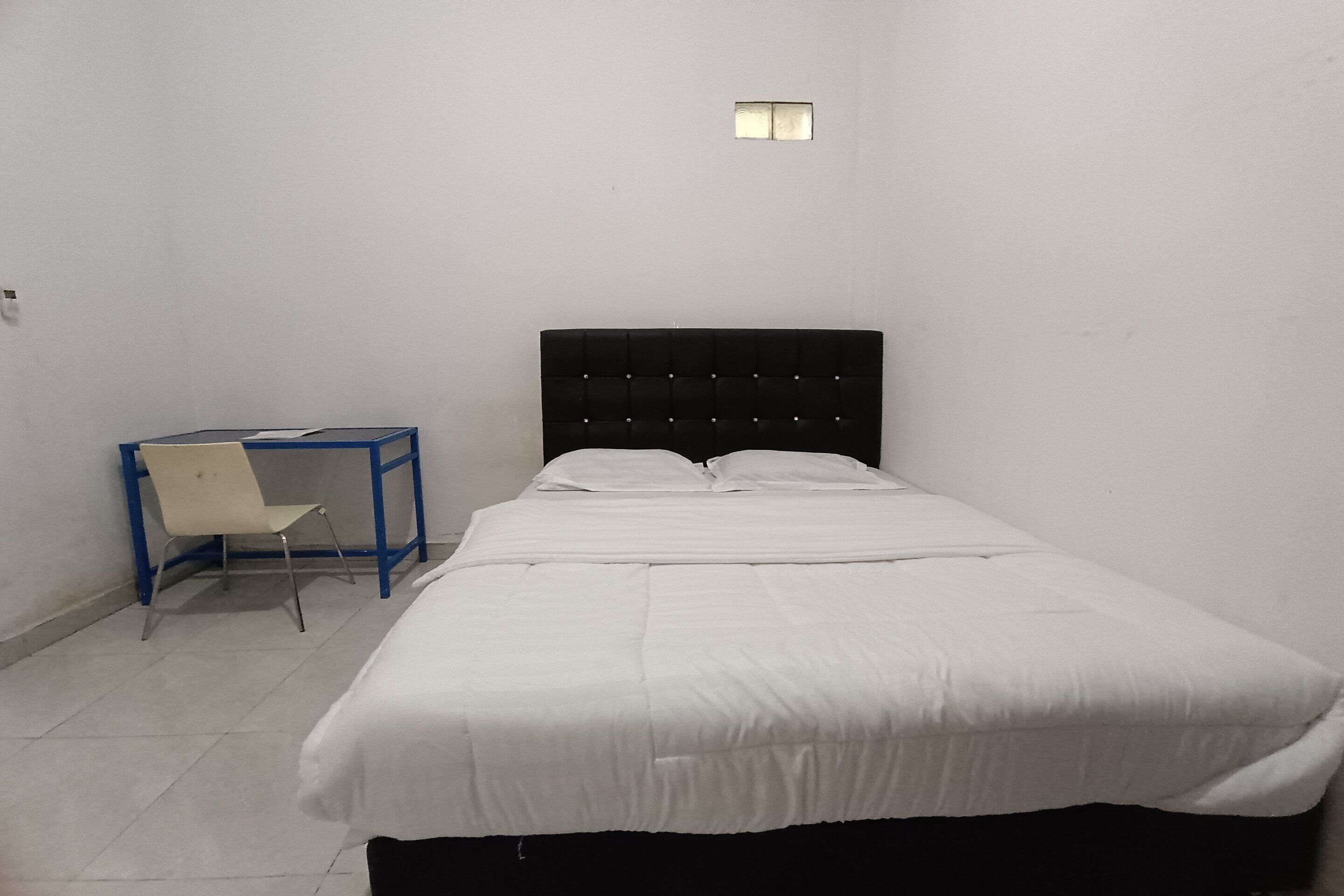 A small, clean room with a single bed, a chair, and a small table.
