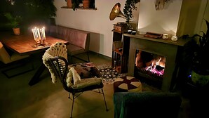 A cozy living room with a fireplace, a table with candles, and a comfortable chair.