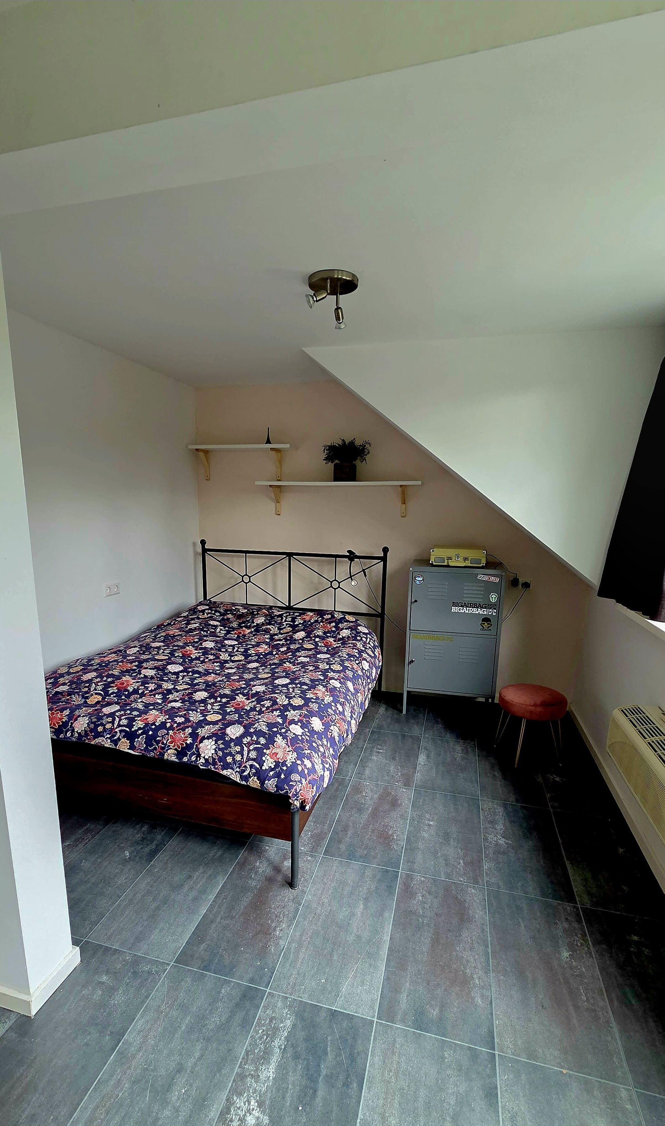 A bedroom with a bed, a nightstand, a heater, and a ceiling fan.