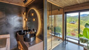 A modern bathroom with a large mirror, two sinks, and a round bathtub. - Awesome home in Norheimsund with sauna (Norheimsund)