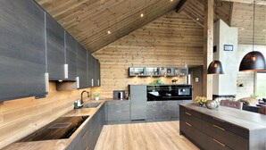 A modern kitchen with dark cabinets, a wooden ceiling, and a central island with seating. - Awesome home in Norheimsund with sauna (Norheimsund)