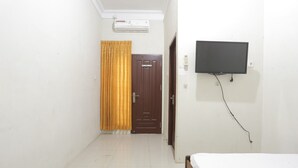 A room with a bed, a television mounted on the wall, a door, and an air conditioning unit. - Hotel O Penginapan Budhe Sri (Koealabadak)