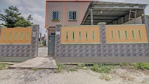 A two-story building with a brick facade, a flat roof, and a gated entrance. - Hotel O Penginapan Budhe Sri (Koealabadak)