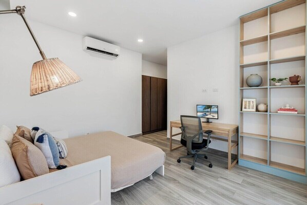 Ein Schlafzimmer mit Bett, Schreibtisch, Stuhl und Bücherregal.