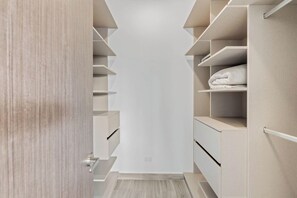 Ein begehbarer Kleiderschrank mit offenen Regalen und Schubladen, eine Holztür und ein heller Boden.
