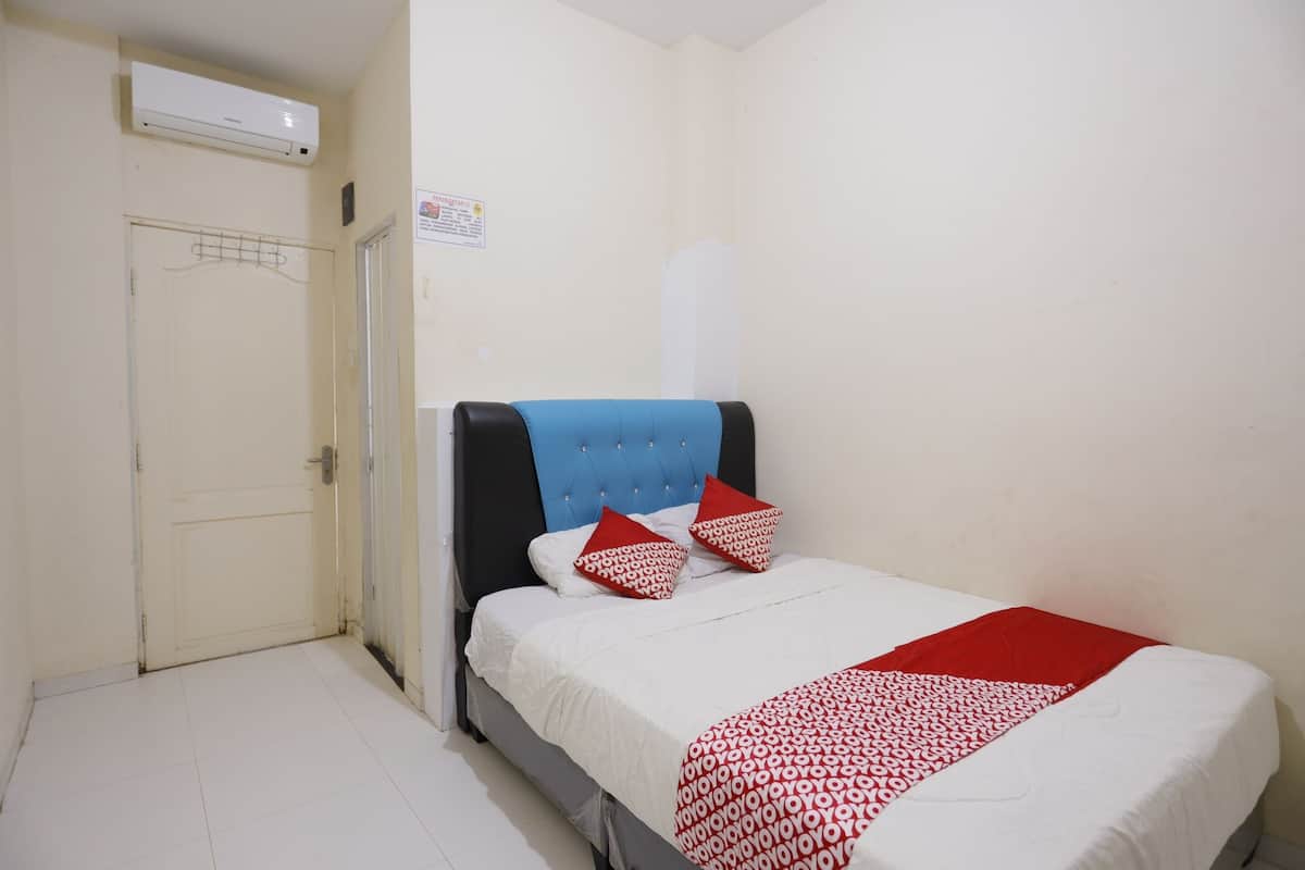Un dormitorio con una cama, una puerta blanca, un aire acondicionado instalado en la pared y un letrero en la pared.