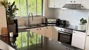 Una cocina moderna con una isla grande, electrodomésticos de acero inoxidable y un ventanal con persianas.