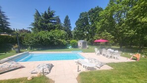 Un patio trasero con piscina, un cobertizo pequeño y mobiliario exterior.