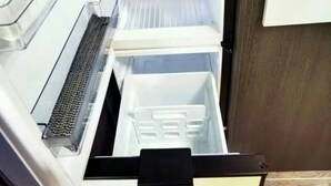 Un refrigerador abierto con varias estantes y un compartimento congelador.