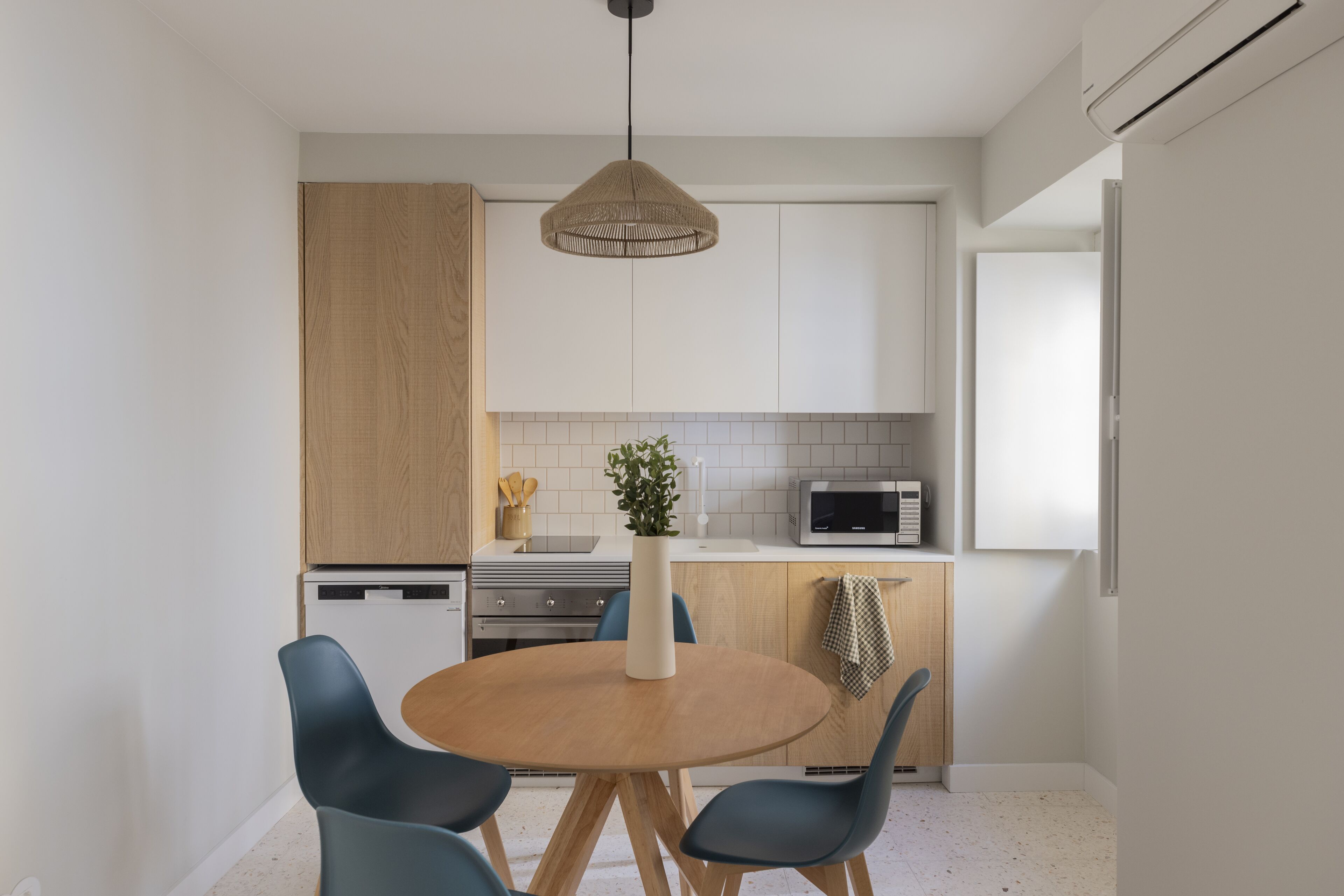 Una cocina moderna con armarios blancos, una mesa de comedor de madera y sillas azules.