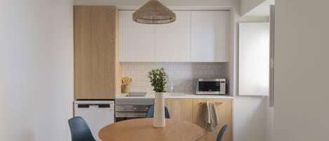 Una cocina moderna con armarios blancos, una mesa de comedor de madera y sillas azules.