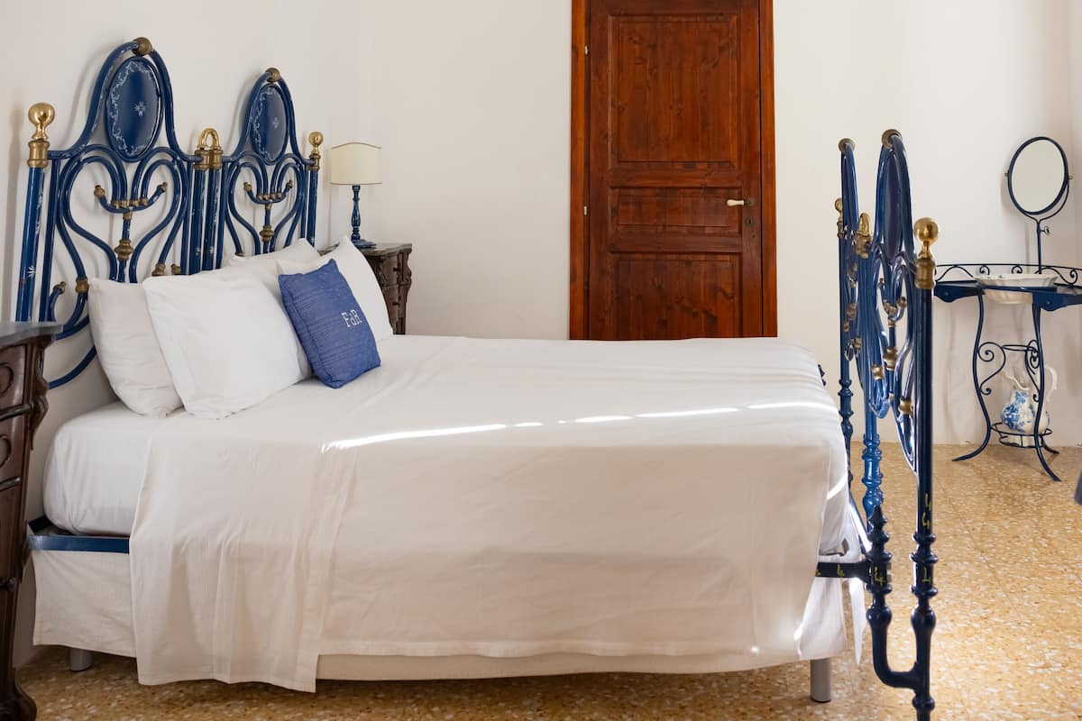 A bedroom with a bed, a wooden door, and a small table with a mirror.