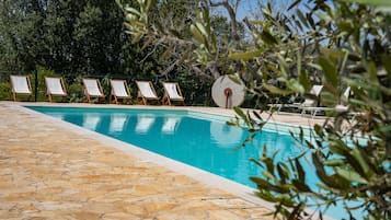 Una piscina al aire libre de temporada, sillones reclinables de piscina