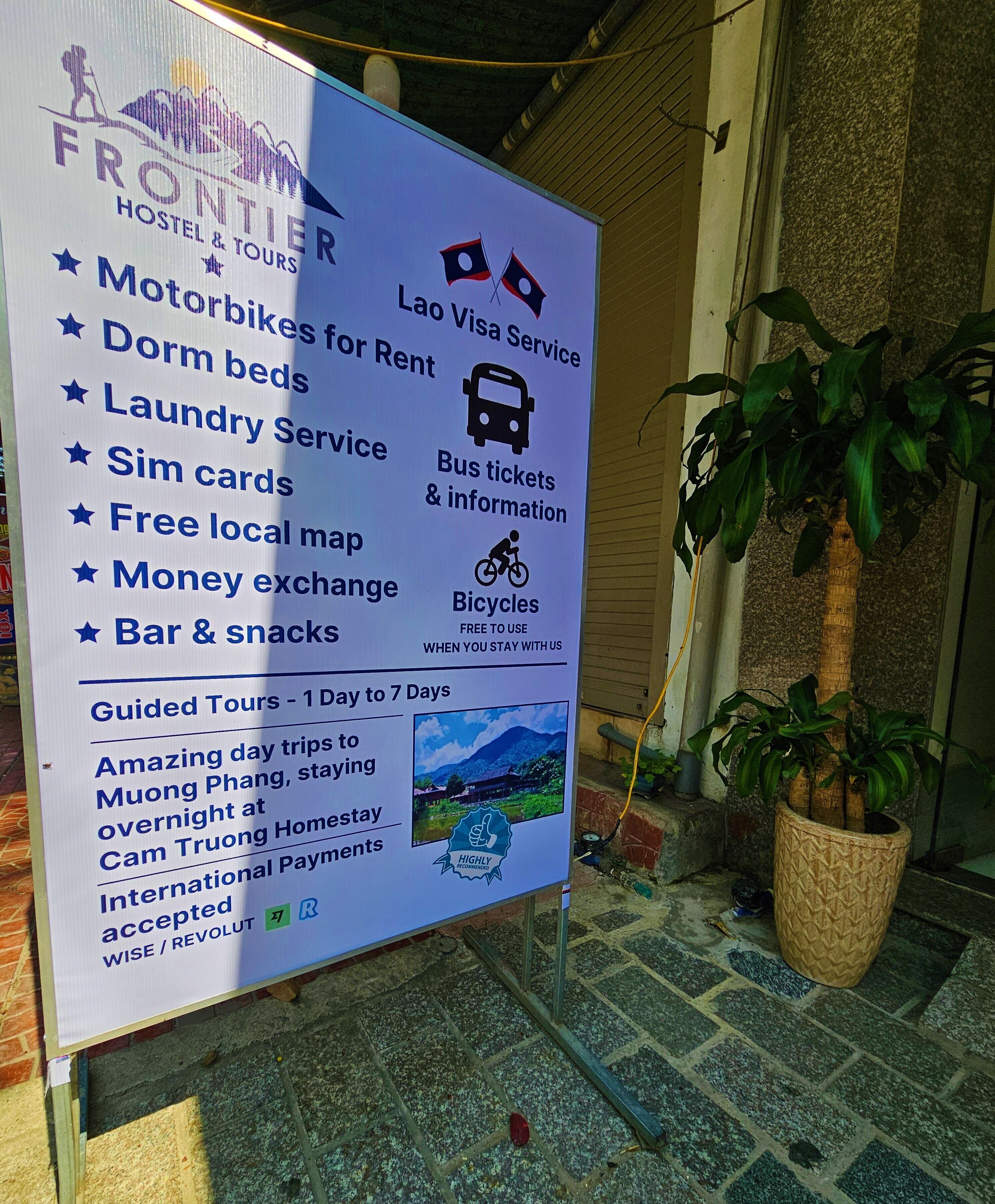 A sign listing amenities such as motorbikes for rent, dorm beds, laundry service, sim cards, free local map, money exchange, bar & snacks, and guided tours.