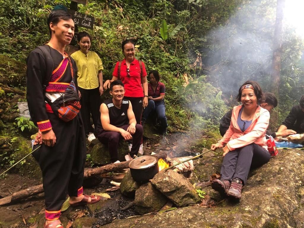 A group of people around a campfire in a forested area.