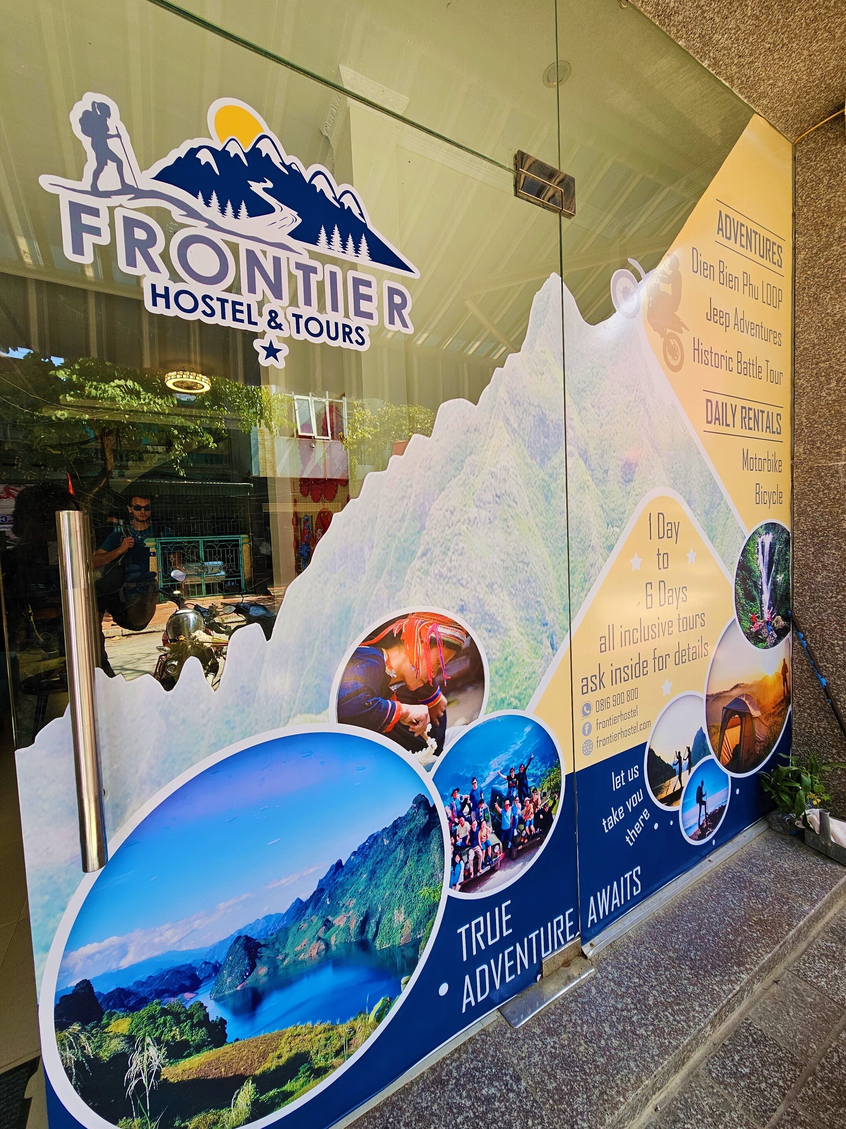 Et hostel med et skilt med bjergtema og et glasvindue der spejler indretningen.