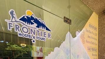 Et hostel med et skilt med bjergtema og et glasvindue der spejler indretningen.