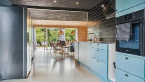 Eine moderne Küche mit blauen Schränken, einem schwarzen Backofen und einem Essbereich mit Korbstühlen und einem Tisch.