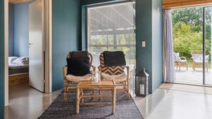 Ein Zimmer mit einem Bett, zwei Stühlen, einem Tisch und einem Fenster mit Blick auf Grünflächen.