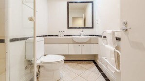 Un baño con inodoro, lavamanos, espejo y bañera.
