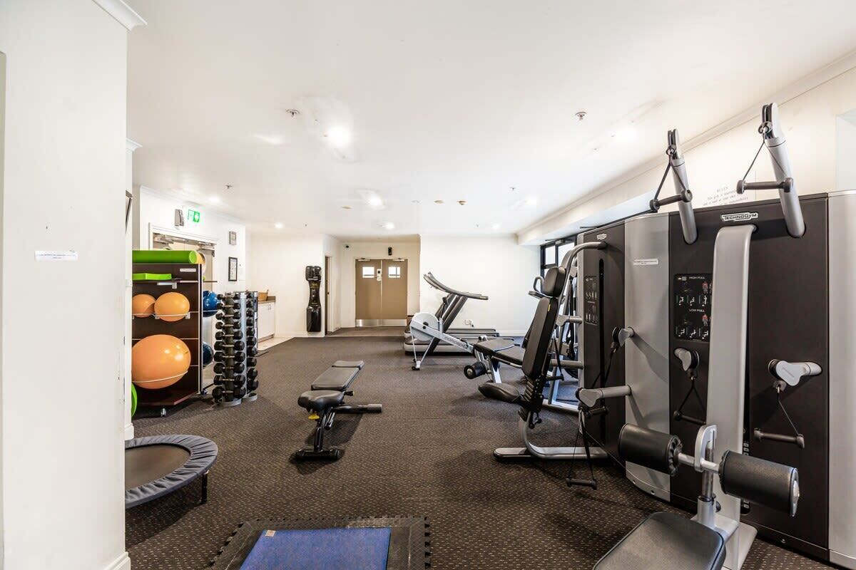 A gym with exercise equipment, a treadmill, and a wall-mounted machine.