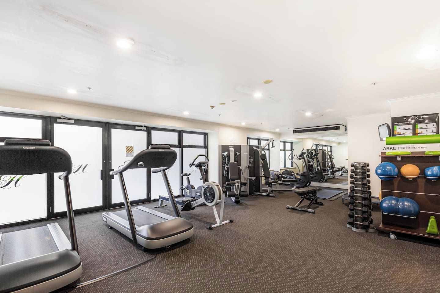 Un gimnasio con cintas de correr, máquinas de pesas y pelotas de ejercicio.