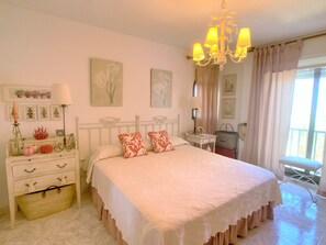Un dormitorio con cama, mesita de noche, lámpara y objetos decorativos.