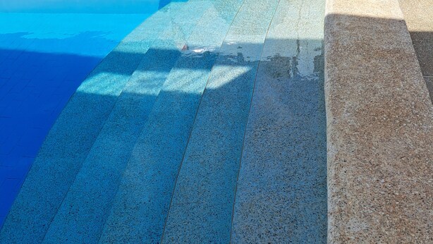 A pool with a blue tiled floor and a stone border. - Villa Neuve, Aérée et Confortable (Nianing)