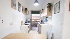 A compact kitchen with a dining table, chairs, and a small island. - Lovely Apartment in Hip and Vibrant Pigneto (Roma)