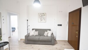 A living room with a grey sofa, patterned cushions, a pendant light, and a framed artwork on the wall. - Lovely Apartment in Hip and Vibrant Pigneto (Roma)